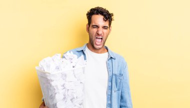 İspanyol yakışıklı adam agresif bir şekilde bağırıyor, çok kızgın görünüyor. kağıt toplar çöp konsepti
