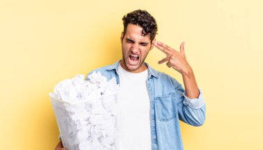 İspanyol yakışıklı adam mutsuz ve stresli görünüyor, intihar jesti silah işareti yapıyor. kağıt toplar çöp konsepti