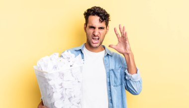 İspanyol yakışıklı adam ellerini havaya kaldırarak bağırıyor. kağıt toplar çöp konsepti