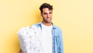 İspanyol yakışıklı adam şaşkın ve şaşkın hissediyor. kağıt toplar çöp konsepti