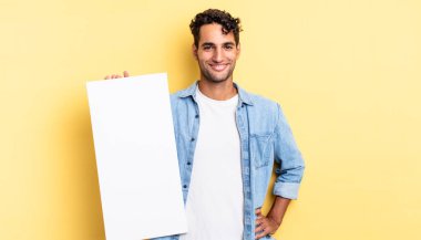 İspanyol yakışıklı adam mutlu bir şekilde gülümsüyor, eli kalçasında ve kendinden emin. boş tuval kavramı