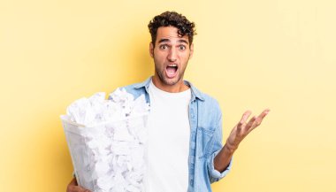 İspanyol yakışıklı adam son derece şaşırmış ve şok olmuş hissediyor. kağıt toplar çöp konsepti
