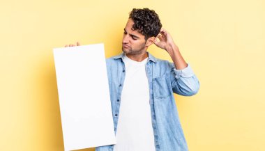 İspanyol yakışıklı adam mutlu bir şekilde gülümsüyor ve hayal kuruyor ya da şüphe ediyor. boş tuval kavramı