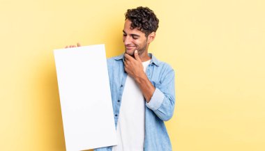 Mutlu, kendine güvenen, elleri çenesinde gülümseyen İspanyol yakışıklı bir adam. boş tuval kavramı