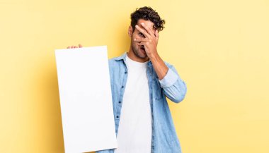 İspanyol yakışıklı adam şok olmuş, korkmuş ya da korkmuş görünüyor. Yüzü elle kapatılmış. boş tuval kavramı