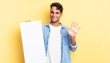 İspanyol yakışıklı adam gülümsüyor ve arkadaş canlısı görünüyor, beş numarayı gösteriyor. boş tuval kavramı
