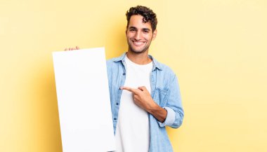 İspanyol yakışıklı adam neşeyle gülümsüyor, mutlu hissediyor ve bir tarafı işaret ediyor. boş tuval kavramı