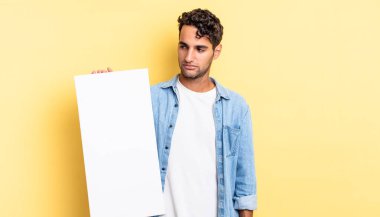 Hispanik yakışıklı adam üzgün, üzgün ya da kızgın hissediyor ve yana bakıyor. boş tuval kavramı