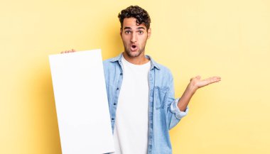 İspanyol yakışıklı adam şaşırmış ve şok olmuş görünüyor. Çenesi düşmüş ve elinde bir nesne var. boş tuval kavramı