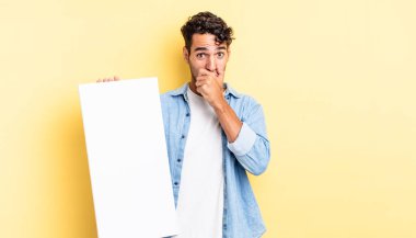 İspanyol yakışıklı adam şok olmuş bir şekilde ağzını kapatıyor. boş tuval kavramı