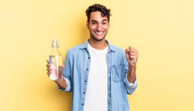 İspanyol yakışıklı adam şokta, gülüyor ve başarıyı kutluyor. su şişesi kavramı