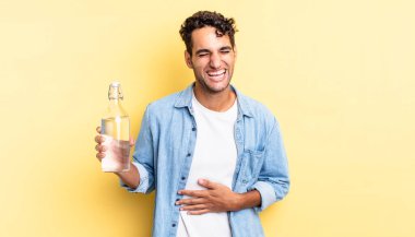 İspanyol yakışıklı bir adam komik bir şakaya yüksek sesle gülüyor. su şişesi kavramı