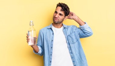 İspanyol yakışıklı adam şaşkın ve kafası karışık, kaşınan bir kafa hissediyor. su şişesi kavramı