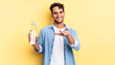 İspanyol yakışıklı adam kamerayı göstererek seni seçiyor. su şişesi kavramı