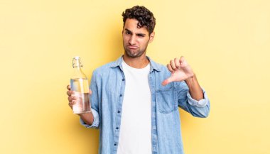 Latin asıllı yakışıklı adam kızgın, baş parmağını kaldırıyor. su şişesi kavramı