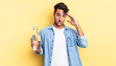 İspanyol yakışıklı adam mutlu, şaşkın ve şaşırmış görünüyor. su şişesi kavramı