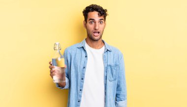 İspanyol yakışıklı adam çok şaşırmış ya da şaşkın görünüyor. su şişesi kavramı