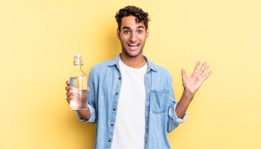 İspanyol yakışıklı adam kendini mutlu hissediyor ve inanılmaz bir şeye hayret ediyor. su şişesi kavramı