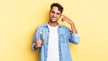 İspanyol yakışıklı adam kafası karışık ve şaşkın hissediyor, senin deli olduğunu gösteriyor. su şişesi kavramı