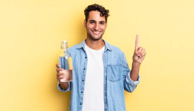 İspanyol yakışıklı adam gülümsüyor ve arkadaş canlısı görünüyor, bir numarayı gösteriyor. su şişesi kavramı