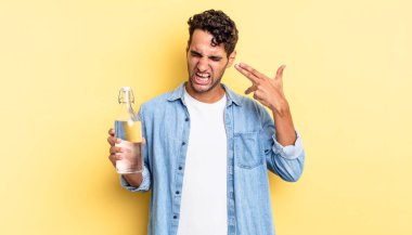 İspanyol yakışıklı adam mutsuz ve stresli görünüyor, intihar jesti silah işareti yapıyor. su şişesi kavramı