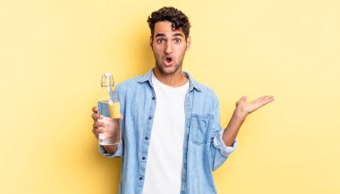 İspanyol yakışıklı adam şaşırmış ve şok olmuş görünüyor. Çenesi düşmüş ve elinde bir nesne var. su şişesi kavramı