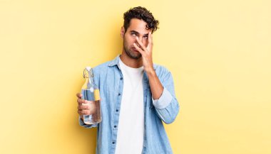 İspanyol yakışıklı bir adam yorgun, bıkkın ve uykulu hissediyor. su şişesi kavramı