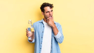 Ağzı ve gözleri açık, eli çenesinde İspanyol yakışıklı bir adam. su şişesi kavramı