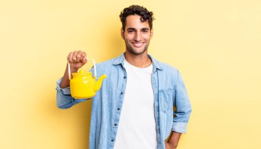 İspanyol yakışıklı adam mutlu bir şekilde gülümsüyor, eli kalçasında ve kendinden emin. çaydanlık konsepti