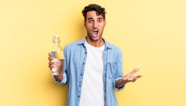 İspanyol yakışıklı adam son derece şaşırmış ve şok olmuş hissediyor. su şişesi kavramı