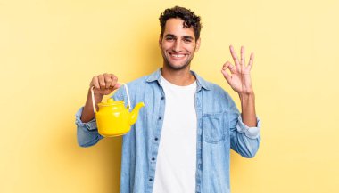 İspanyol yakışıklı adam kendini mutlu hissediyor, iyi bir jestle onaylıyor. çaydanlık konsepti