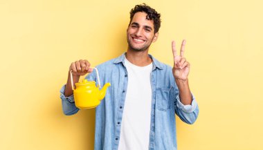 İspanyol yakışıklı adam gülümsüyor ve mutlu görünüyor, zafer ya da barış işareti yapıyor. çaydanlık konsepti