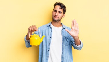 İspanyol yakışıklı adam ciddi görünüyor. Avuç içi gösteriyor. Durdurma hareketi yapıyor. çaydanlık konsepti