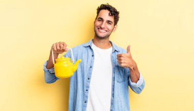 İspanyol yakışıklı adam kendini gururlu hissediyor, başparmağıyla olumlu gülümsüyor. çaydanlık konsepti