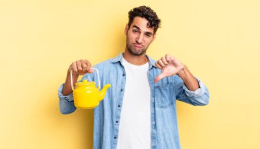 Latin asıllı yakışıklı adam kızgın, baş parmağını kaldırıyor. çaydanlık konsepti