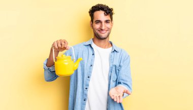 İspanyol yakışıklı adam mutlu bir şekilde gülümsüyor ve bir konsept sunuyor. çaydanlık konsepti