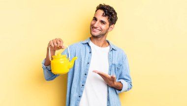 İspanyol yakışıklı adam neşeyle gülümsüyor, mutlu hissediyor ve bir konsept gösteriyor. çaydanlık konsepti