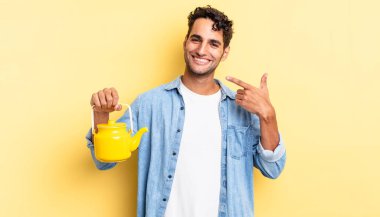 İspanyol yakışıklı adam kendine güvenerek gülüyor ve kendi gülüşüne işaret ediyor. çaydanlık konsepti