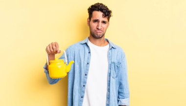 Hispanik yakışıklı adam üzgün ve mızmız, mutsuz bir bakışla ağlıyor. çaydanlık konsepti