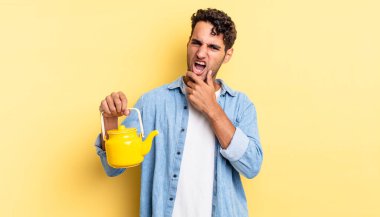 Ağzı ve gözleri açık, eli çenesinde İspanyol yakışıklı bir adam. çaydanlık konsepti