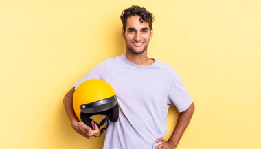 İspanyol yakışıklı adam mutlu bir şekilde gülümsüyor, eli kalçasında ve kendinden emin. Motosiklet kaskı konsepti