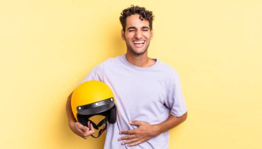 İspanyol yakışıklı bir adam komik bir şakaya yüksek sesle gülüyor. Motosiklet kaskı konsepti