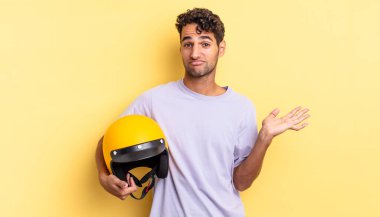 İspanyol yakışıklı adam şaşkın, şaşkın ve şüpheci hissediyor. Motosiklet kaskı konsepti