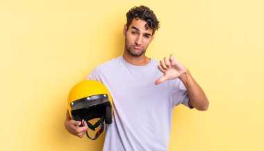 Latin asıllı yakışıklı adam kızgın, baş parmağını kaldırıyor. Motosiklet kaskı konsepti