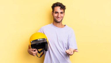 İspanyol yakışıklı adam mutlu bir şekilde gülümsüyor ve bir konsept sunuyor. Motosiklet kaskı konsepti