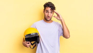 İspanyol yakışıklı adam mutlu, şaşkın ve şaşırmış görünüyor. Motosiklet kaskı konsepti