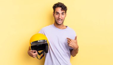 İspanyol yakışıklı adam mutlu hissediyor ve heyecanla kendini işaret ediyor. Motosiklet kaskı konsepti