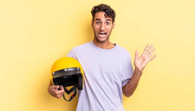 İspanyol yakışıklı adam kendini mutlu hissediyor ve inanılmaz bir şeye hayret ediyor. Motosiklet kaskı konsepti