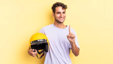 Hispanik yakışıklı adam gururla gülümsüyor ve kendinden emin bir numara oluyor. Motosiklet kaskı konsepti