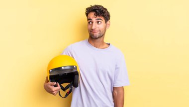 İspanyol yakışıklı adam omuz silkiyor, kafası karışık ve kararsız. Motosiklet kaskı konsepti